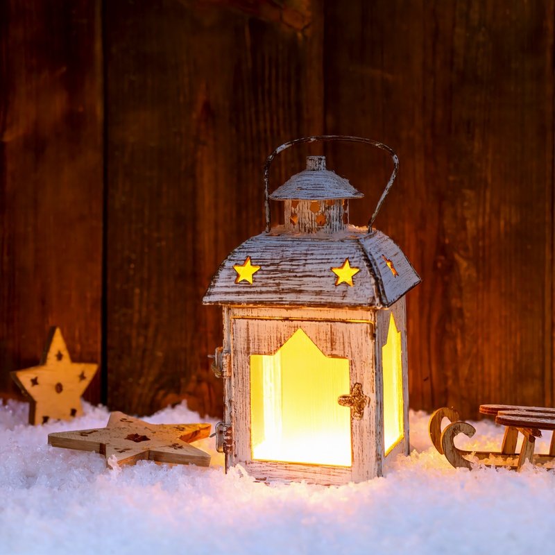 A Lantern With Star Cutouts Illuminating A Festive Scene
