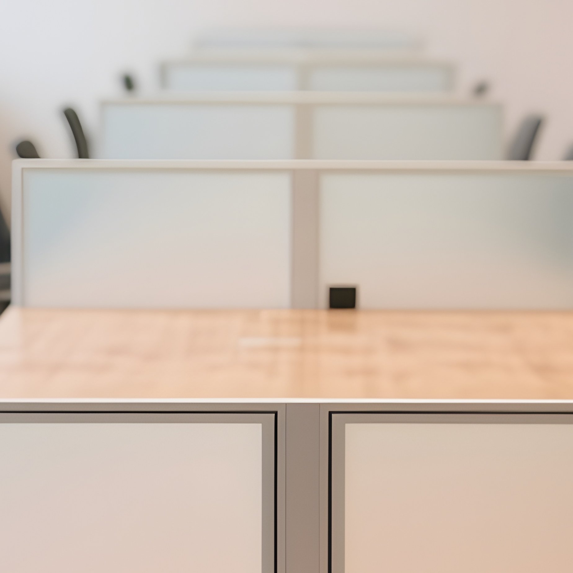 A Long Communal Wooden Table In A Shared Workspace, With Multiple Workstations Separated By Small Frosted Glass Dividers For Privacy. - Full Resolution Quality Preview