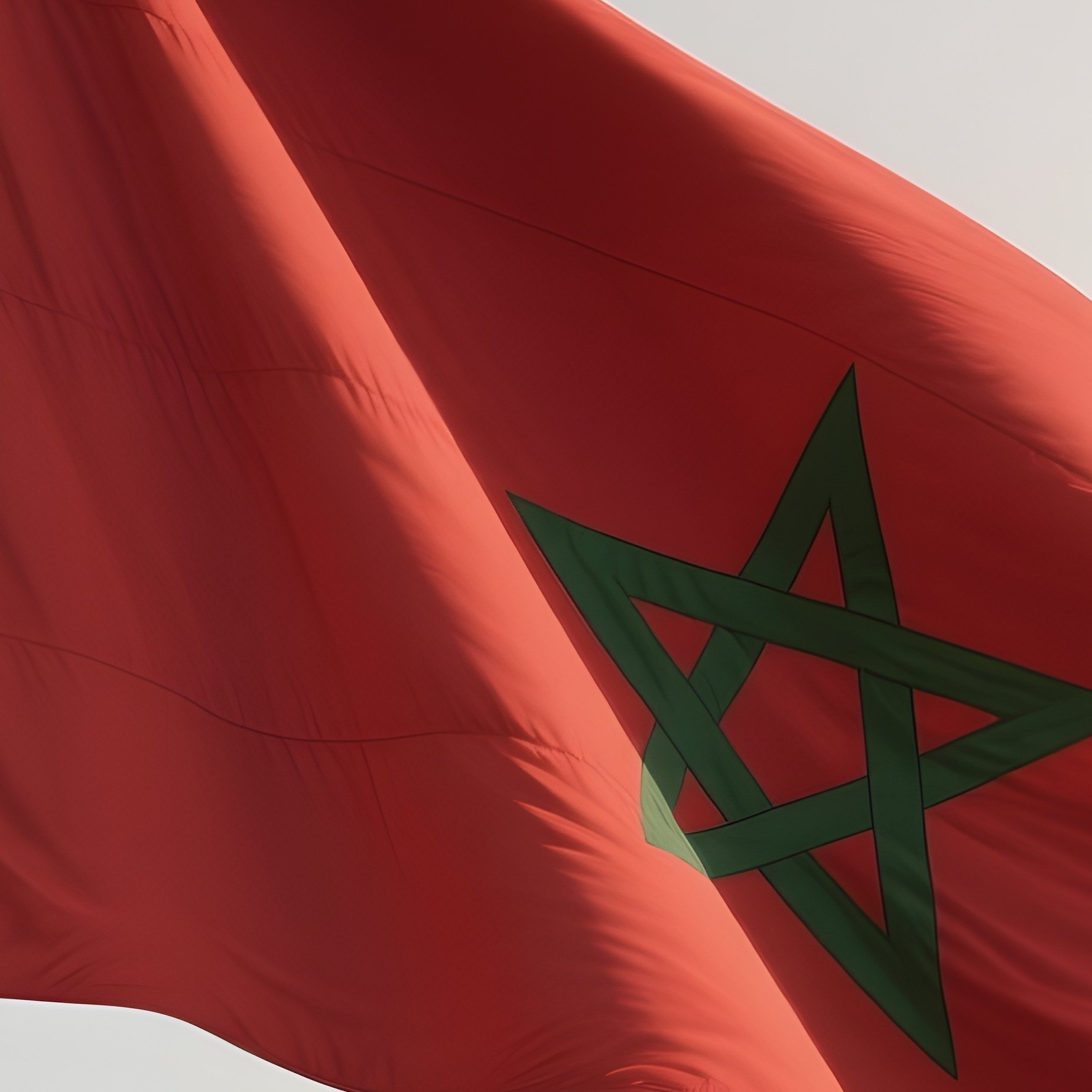 A Photorealistic Scene Of The National Flag Of Morocco Flying At Half Mast On A Tall Flagpole, Gently Lowering In The Wind Against A Respectful, Calm Backdrop With Soft Natural Lighting. - Full Resolution Quality Preview