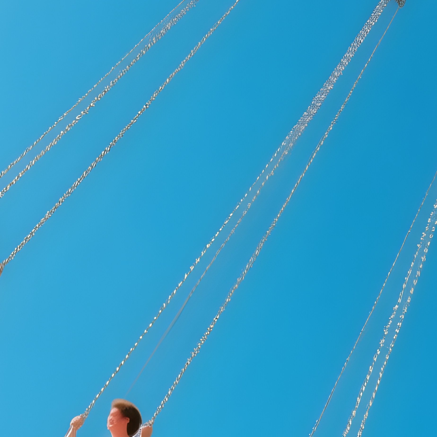 A Swing Ride Spinning High Above The Ground With Legs Dangling Against The Clouds - Full Resolution Quality Preview