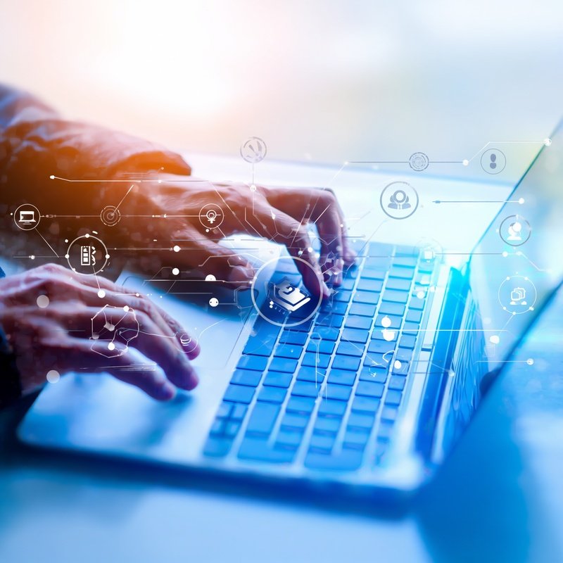 Person Typing On A Laptop Keyboard With Digital Icons Overlay